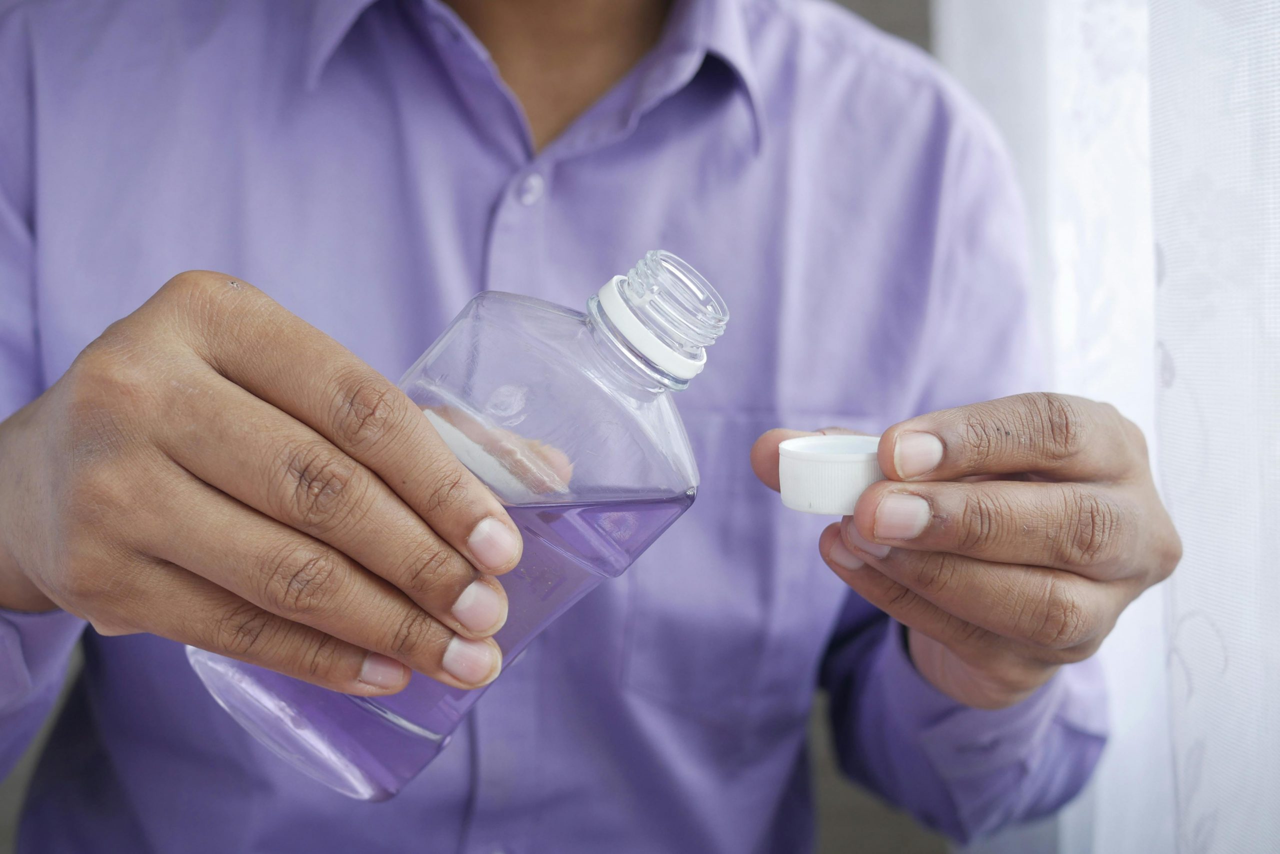 man pouring mouthwash into the cap of the bottle